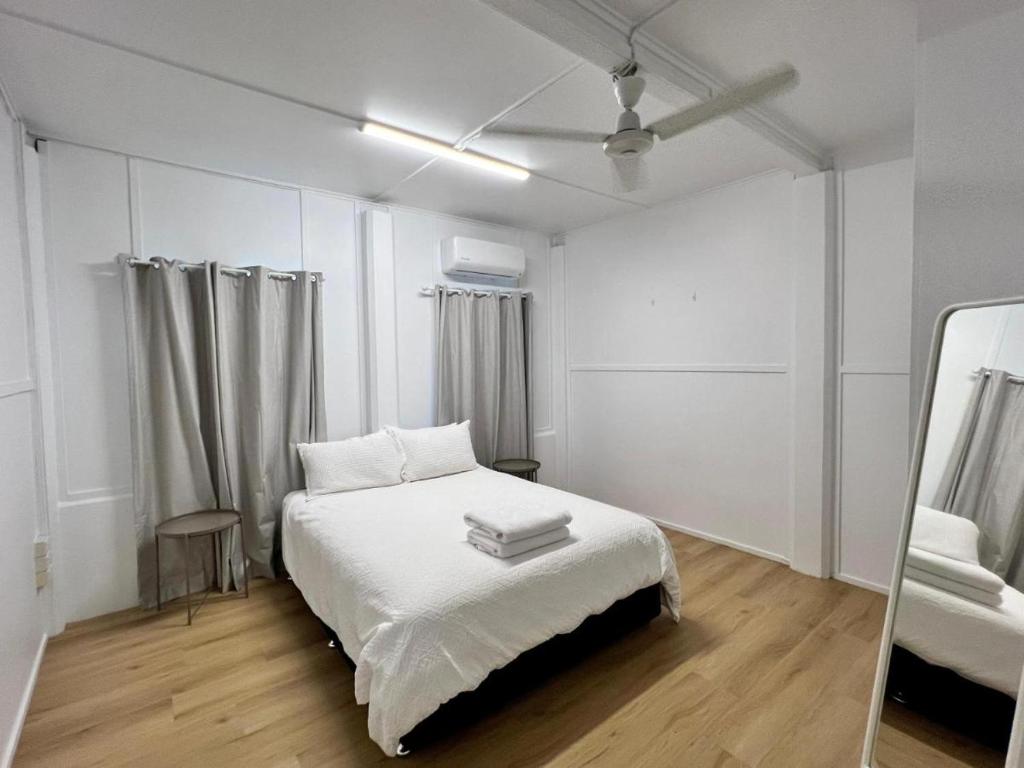 a white bedroom with a bed and a mirror at Townsville Suites in Townsville