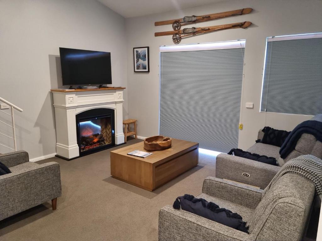 a living room with a fireplace and a tv at Courtyard Loft 12 The Stables Perisher in Perisher Valley