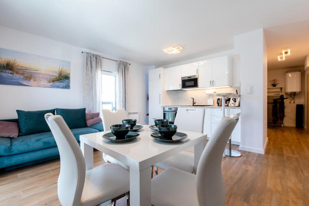 a kitchen and living room with a white table and chairs at Apartament Modern by Major Domus Club in Dziwnów