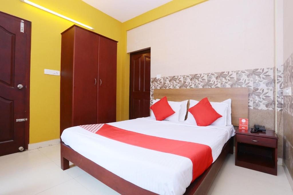 um quarto com uma cama grande e almofadas vermelhas em Hotel Day Springs em Kottayam