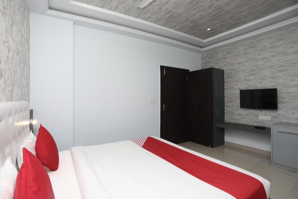 um quarto com uma cama com almofadas vermelhas e uma televisão em Flagship Hotel Mangalam Inn em Izatnagar