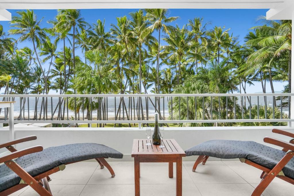 uma varanda com cadeiras, uma mesa e palmeiras em Belle Escapes Sapphire Suite Oceanview 17 Alamanda Palm Cove em Palm Cove
