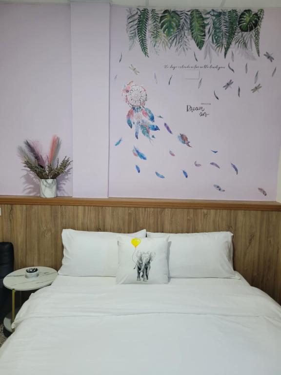 a bed with white sheets and a picture of an elephant at 海戀初衷文旅 近東大門 in Hualien City