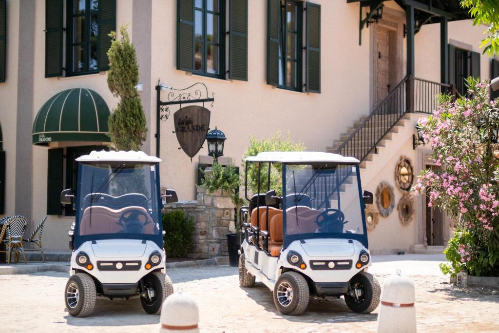 two golf carts parked in front of a building at BİADA OTELLERİ in Bozcaada