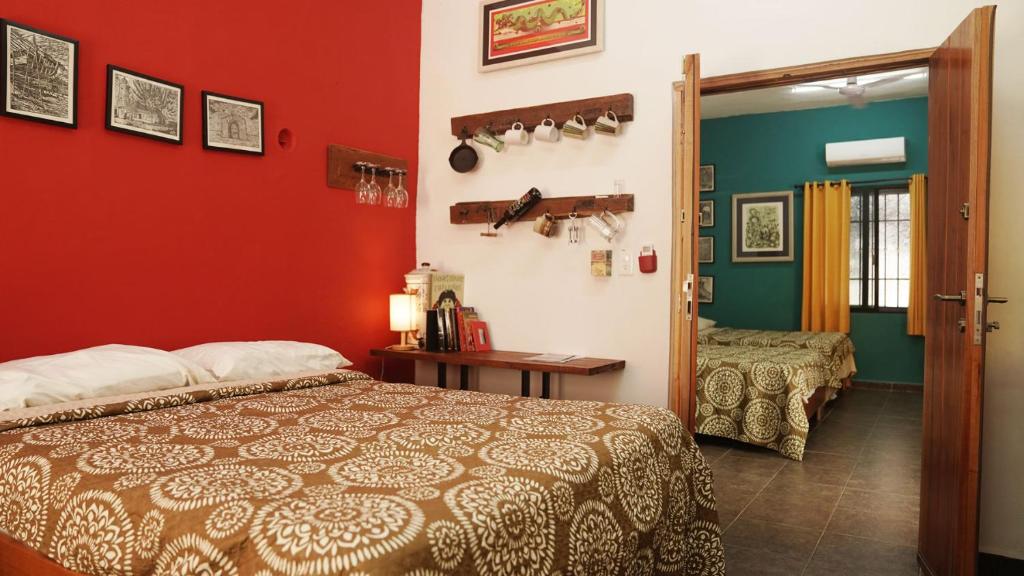 um quarto com uma cama e uma parede vermelha em La Casa del Café em Campeche