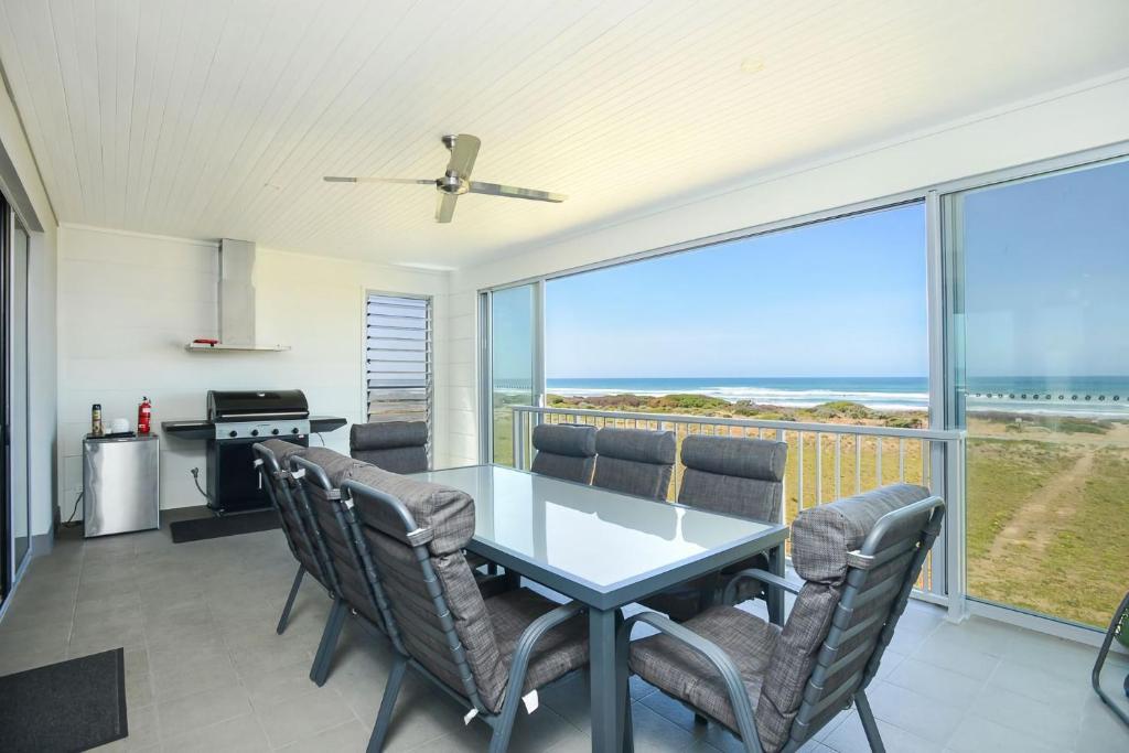 een eetkamer met een tafel en stoelen en de oceaan bij Executive Accommodation Absolute Beach Front in Middleton