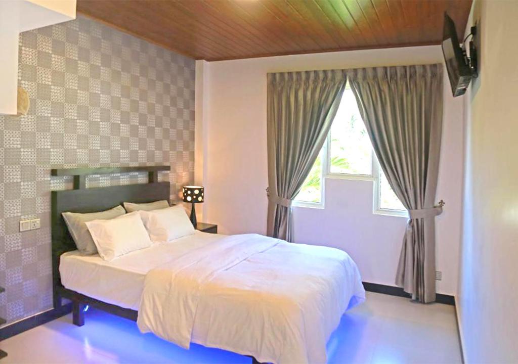 a bedroom with a large white bed with a window at The Branch B&B in Negombo