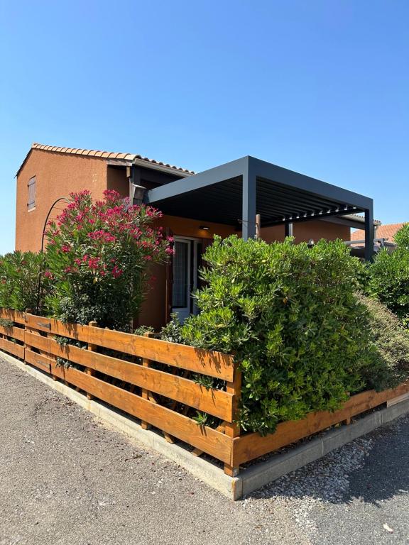 une maison avec une clôture en bois et quelques buissons dans l'établissement Holidayland Résidence Beau Soleil villa avec piscine, à Narbonne-Plage