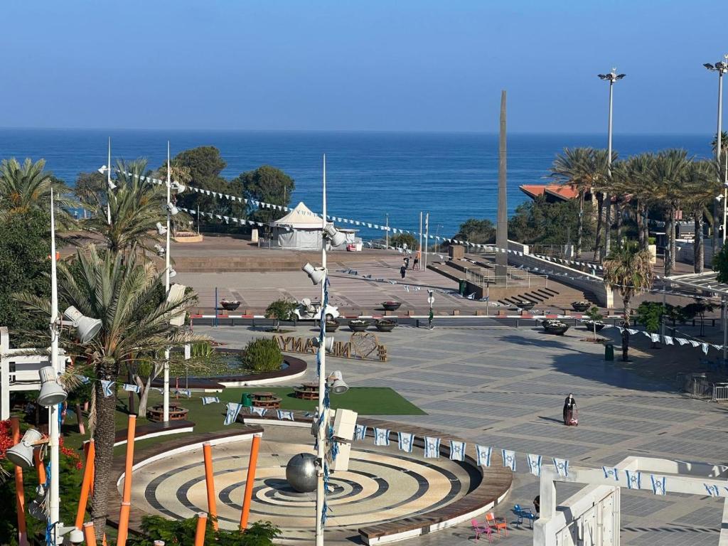 un parque cerca de la playa con el océano en el fondo en חוויה בכיכר en Netanya