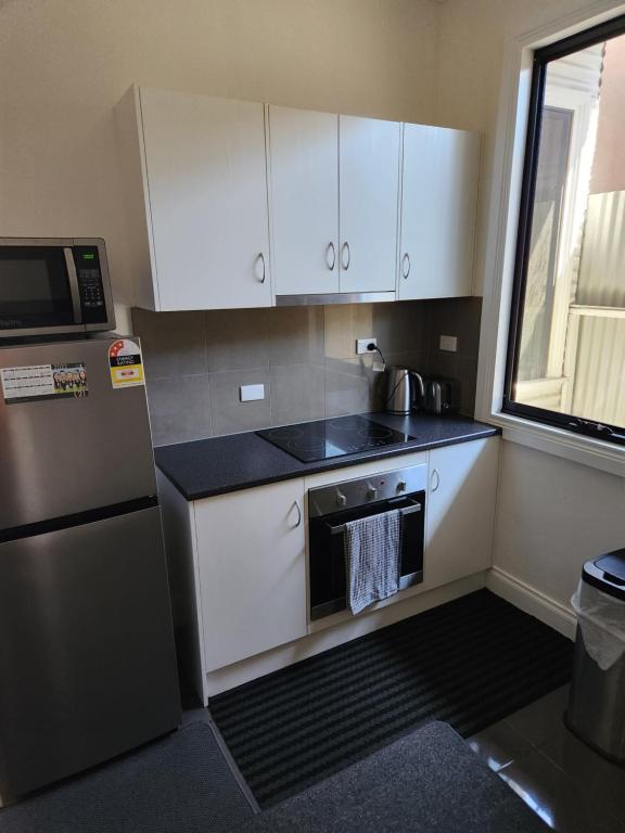 a small kitchen with white cabinets and a refrigerator at City Villa 41 Blende st Broken Hill NSW 2880 in Broken Hill