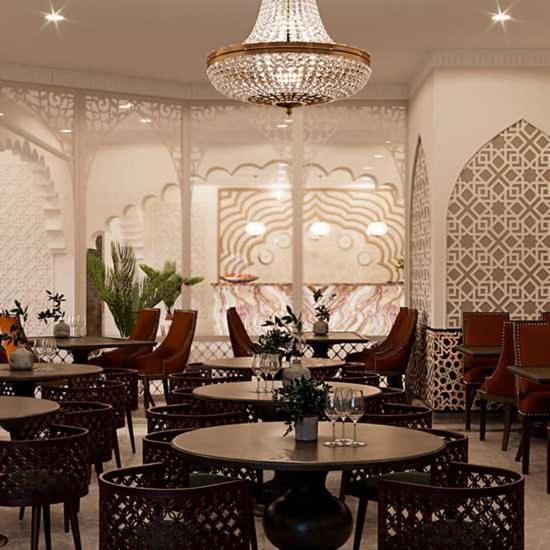 a restaurant with tables and chairs and a chandelier at Reikartz Sote Tashkent in Tashkent