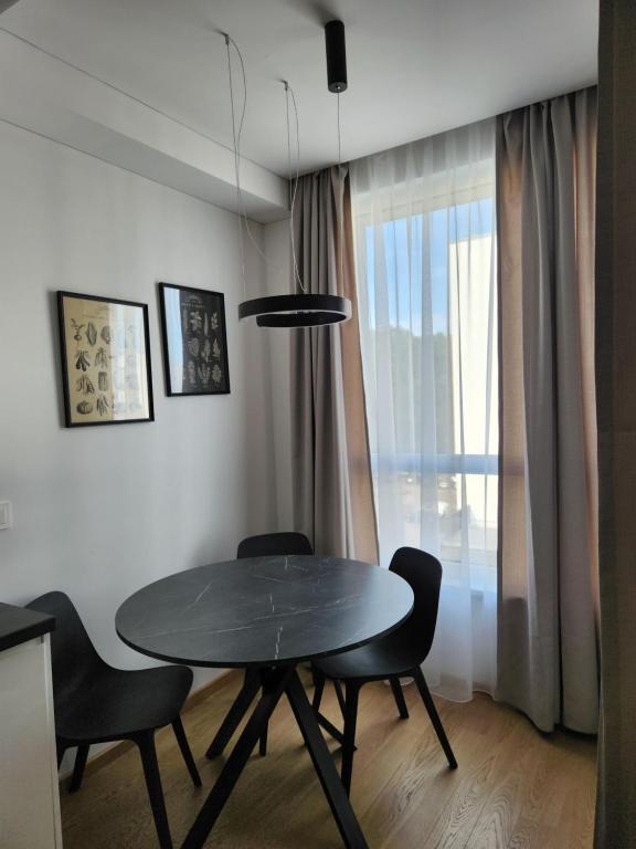 a dining room with a table and chairs and a window at Prie Vilneles Apartment in Vilnius