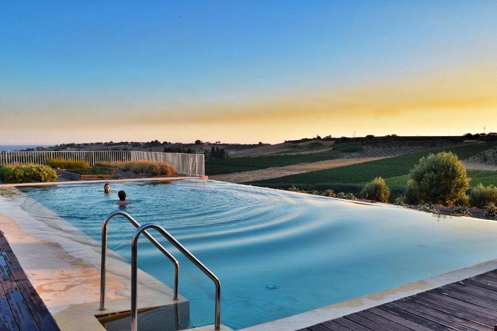 a swimming pool with two people in the water at La Foresteria Planetaestate in Menfi