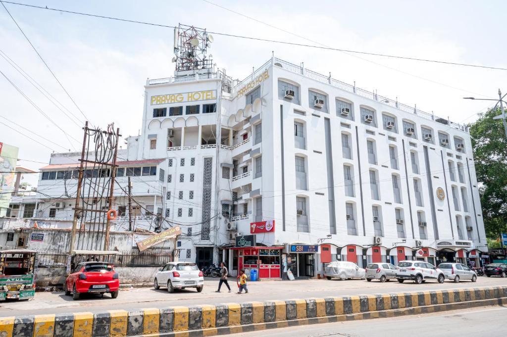 a large white building on a city street with cars at Hotel Prayag in Allahābād