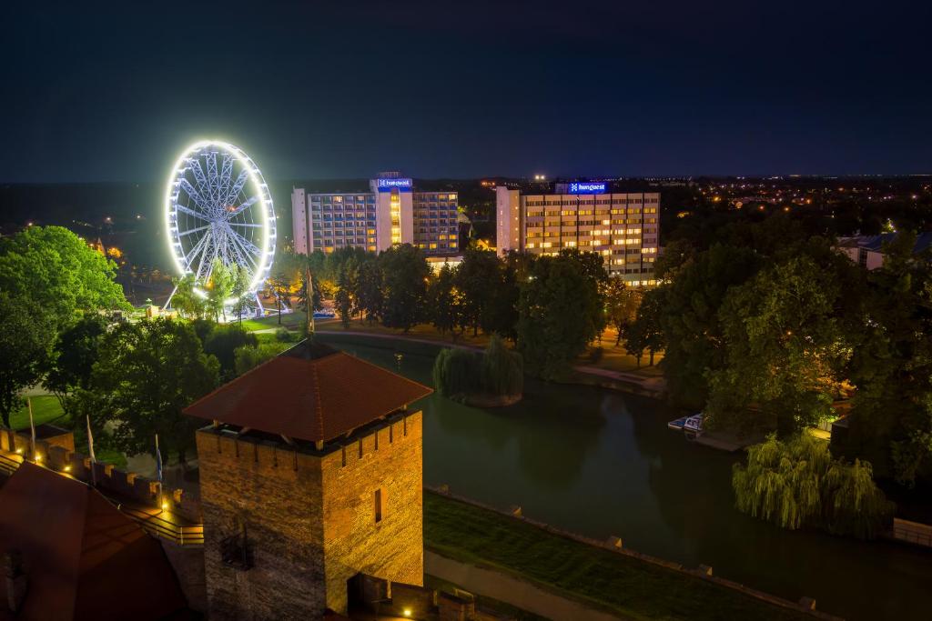 een uitzicht op een stad 's nachts met een reuzenrad bij Hunguest Hotel Gyula in Gyula