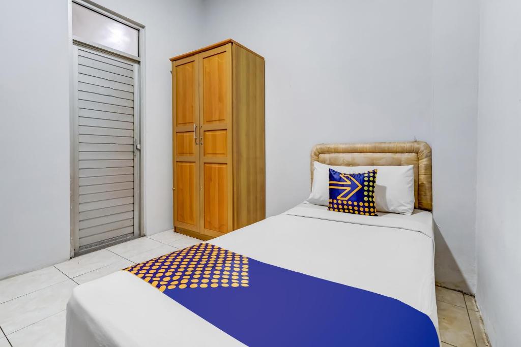 een slaapkamer met een bed en een houten kast bij Super OYO 91366 The Chatter Place in Bandung