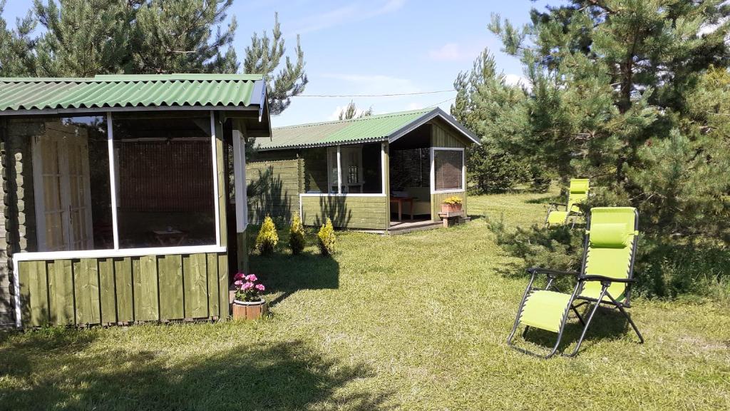 a house with a green roof and chairs in the yard at Kastani Camping in Haapsalu