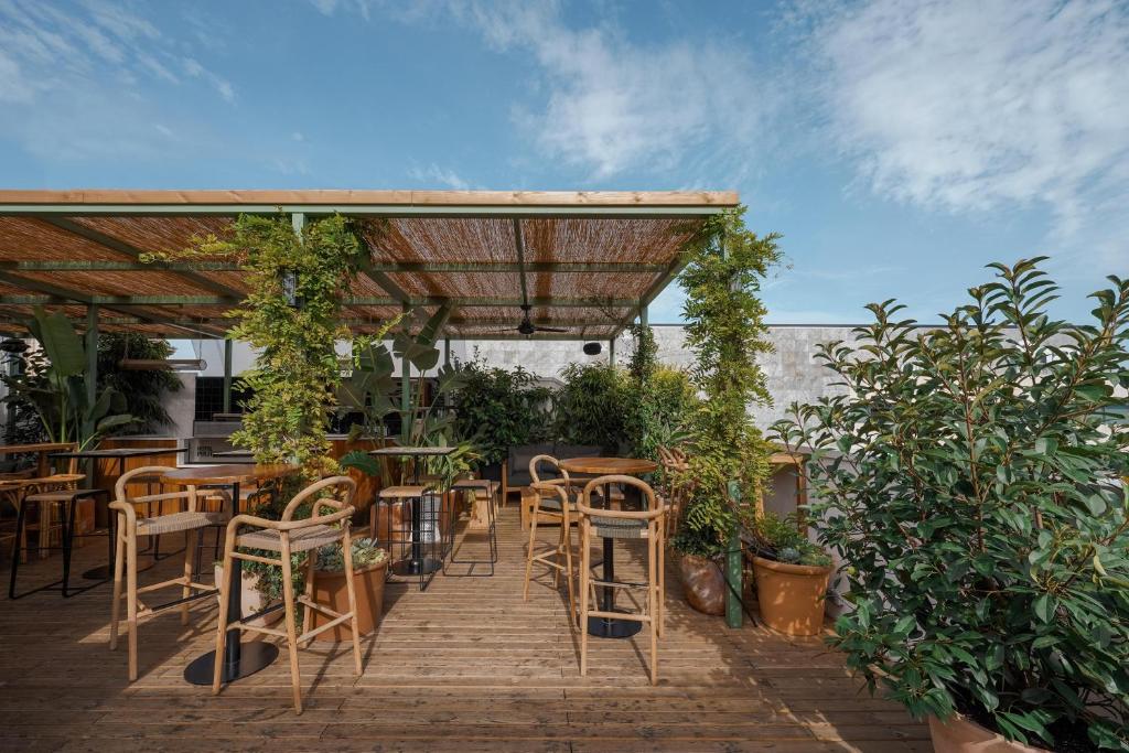 eine Terrasse mit Tischen und Stühlen unter einer Pergola in der Unterkunft Hotel Pulitzer Barcelona in Barcelona