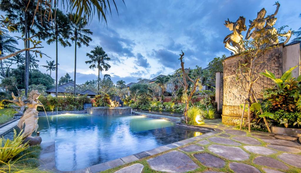 una piscina en un complejo con árboles y un edificio en Anumana Village Ubud, en Ubud