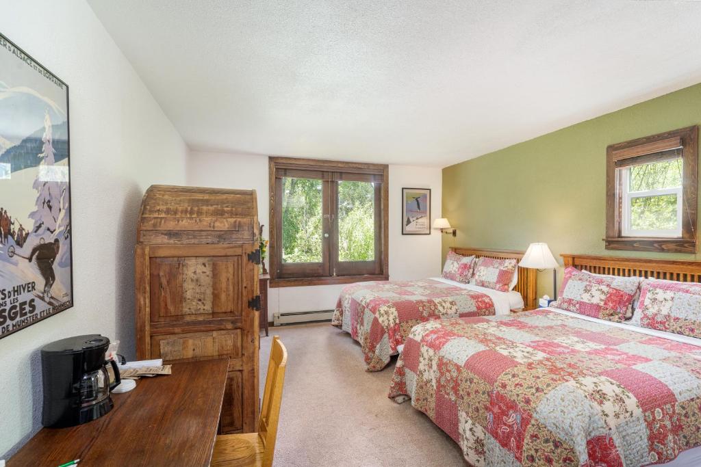 a bedroom with two beds and a table and a desk at Manitou Lodge 3 Hotel Room in Telluride