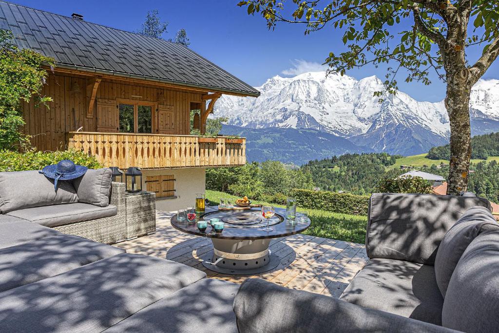 un patio con mesa y vistas a la montaña en CHALET LES CERISES Jacuzzi, Sauna, Hammam, Cinéma, en Cordon