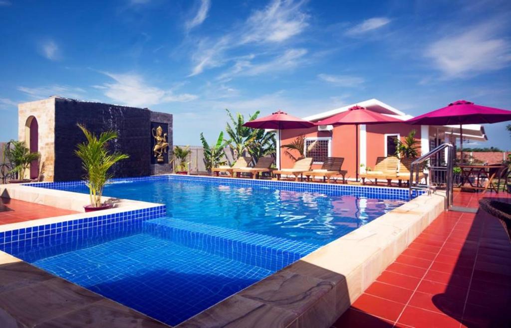 une grande piscine avec des parasols et un complexe dans l'établissement Sun Boutique Resort & Restaurant, à Siem Reap