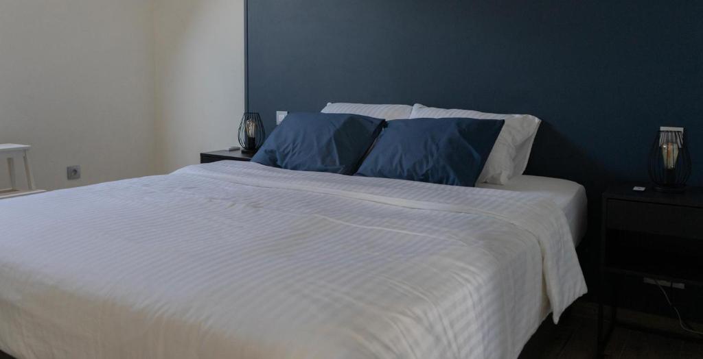 a bedroom with a white bed with two blue pillows at Au Petit Canteleu - Bed & Breakfast in Beloeil