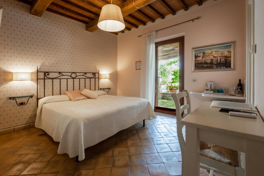 a bedroom with a bed and a desk and a window at Cerchio Verde in Pitigliano