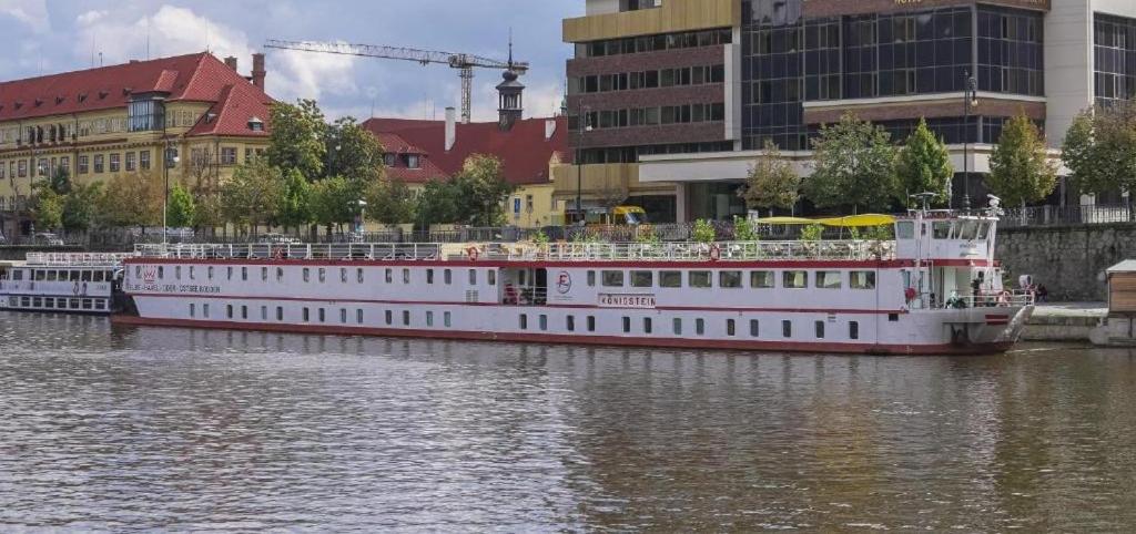 un grand bateau est amarré sur une rivière avec des bâtiments dans l'établissement River hotel KÖNIGSTEIN, à Prague