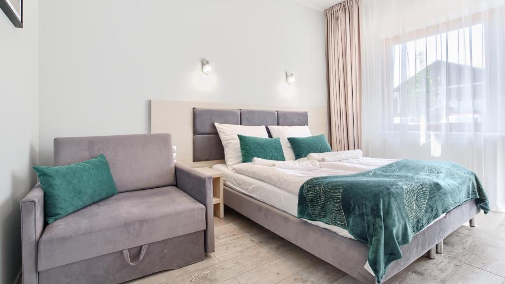 a bedroom with a bed and a chair at Apartamenty Sun & Snow Family Dominikana Resort & SPA in Sianozety