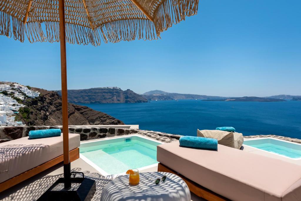 a villa with a swimming pool and an umbrella at Twenty One Suites in Oia