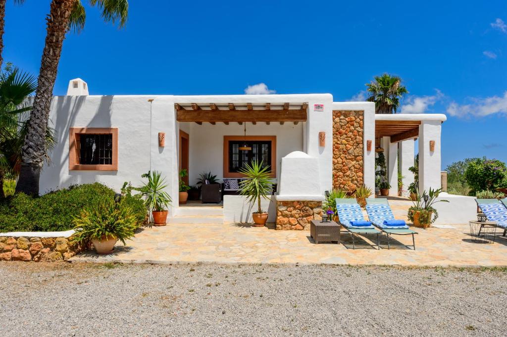 a white house with blue chairs and palm trees at Villa Cana Clara in Sant Carles de Peralta