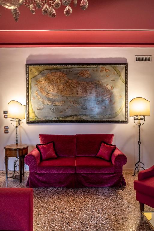 a living room with a red couch and a large painting on the wall at Excess Venice Boutique Hotel & Private Spa - Adults Only in Venice