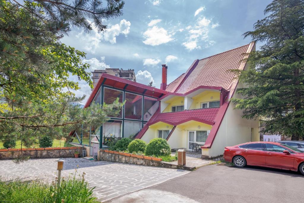un coche rojo estacionado frente a una casa en EcoRest - Likani Palace, en Borjomi