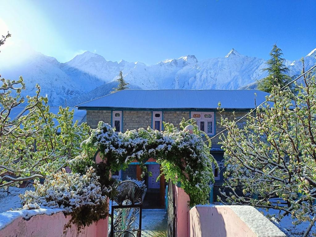 Una casa con una corona sobre una puerta con montañas. en Farmvilla Homestay, en Kalpa