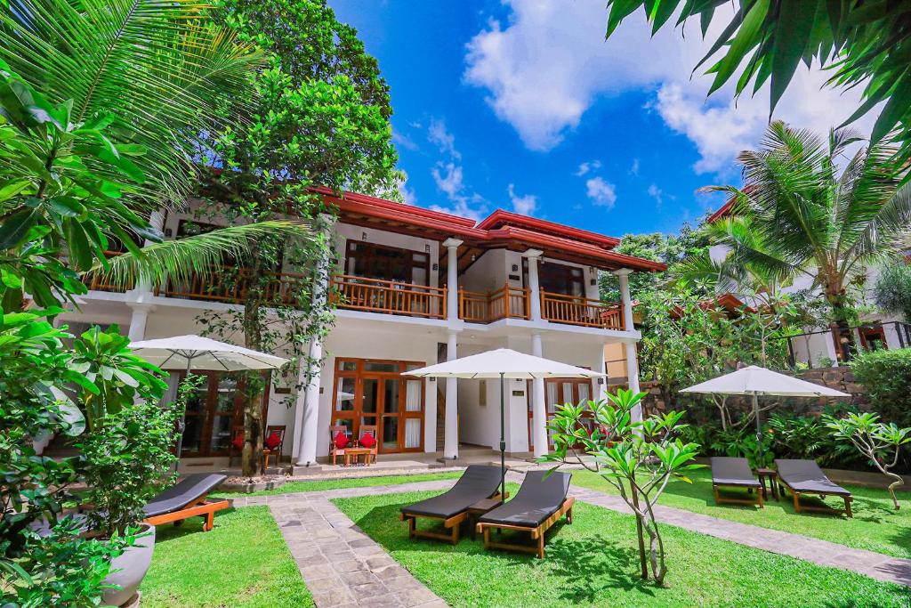 a house with chairs and umbrellas in front of it at Terrace Garden Ayurveda Resort in Weligama