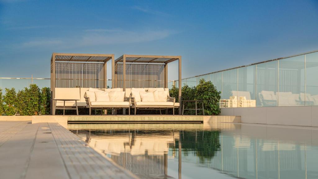 a pool of water with two white chairs next to a building at Port Alicante City & Beach in Alicante