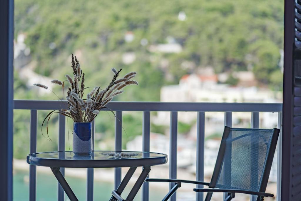 een tafel en stoelen op een balkon met een vaas met bloemen bij Levantes Hotel in Patitiri