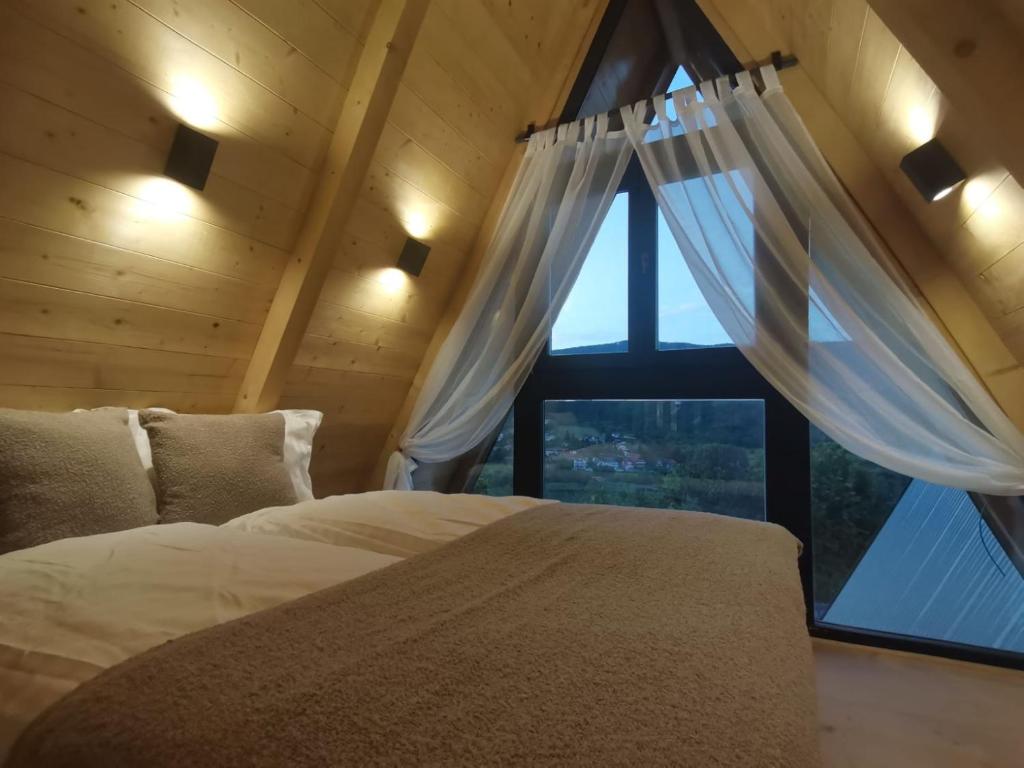 um quarto com uma cama e uma grande janela em Stone Chalets LUNA em Jajce