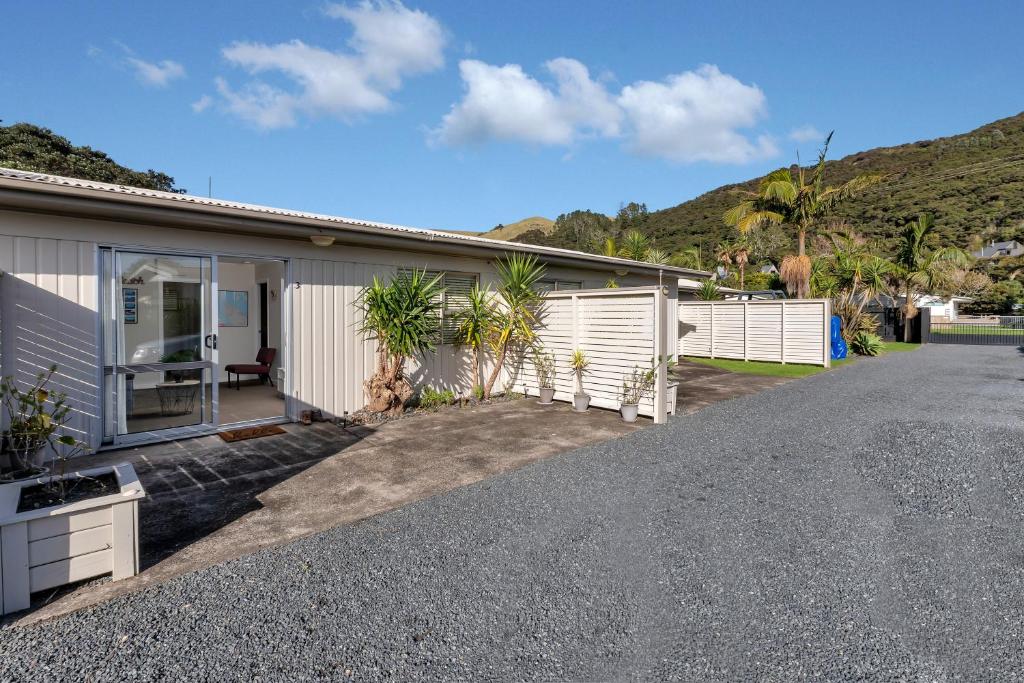 a house with a gravel driveway in front of it at Beach Daze - Tauranga Bay Holiday Unit in Mahinepua