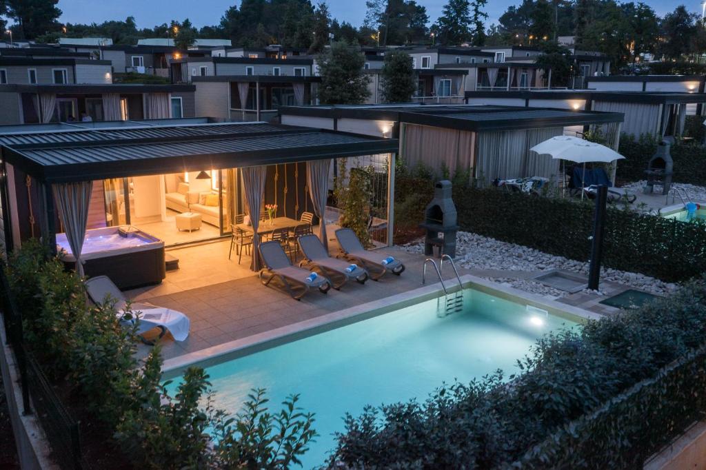 a swimming pool in a backyard with chairs and an umbrella at Premium Camping Homes Santa Marina, Lanterna in Poreč