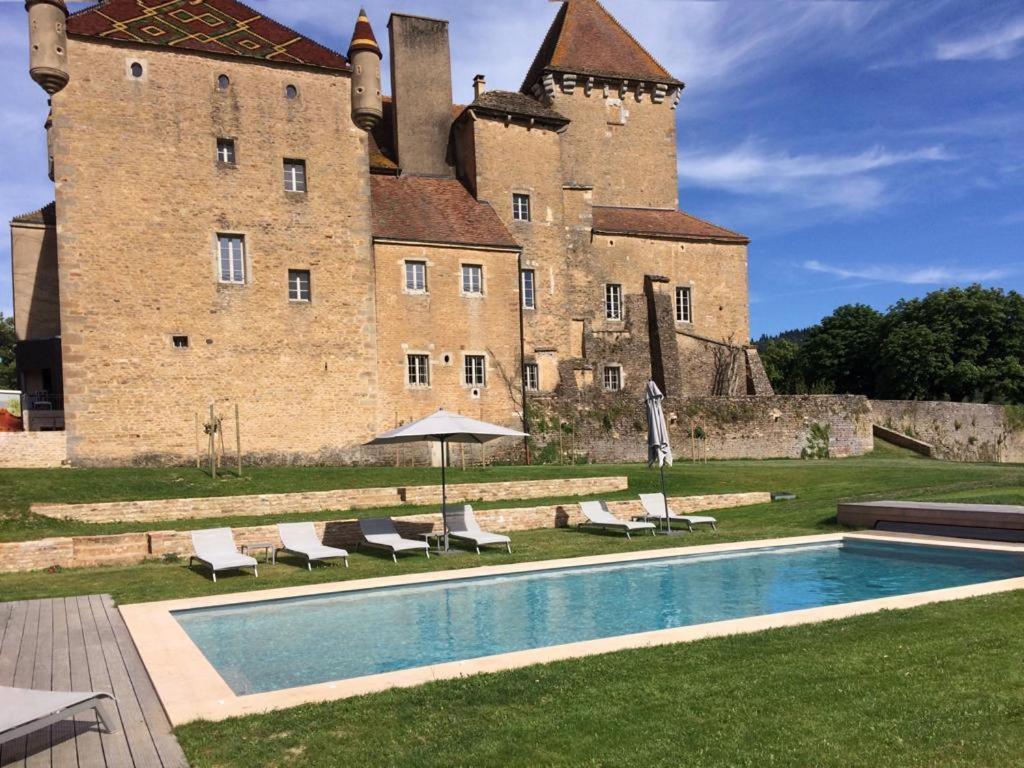 un castillo con piscina frente a un edificio en Château de Pierreclos, en Pierreclos