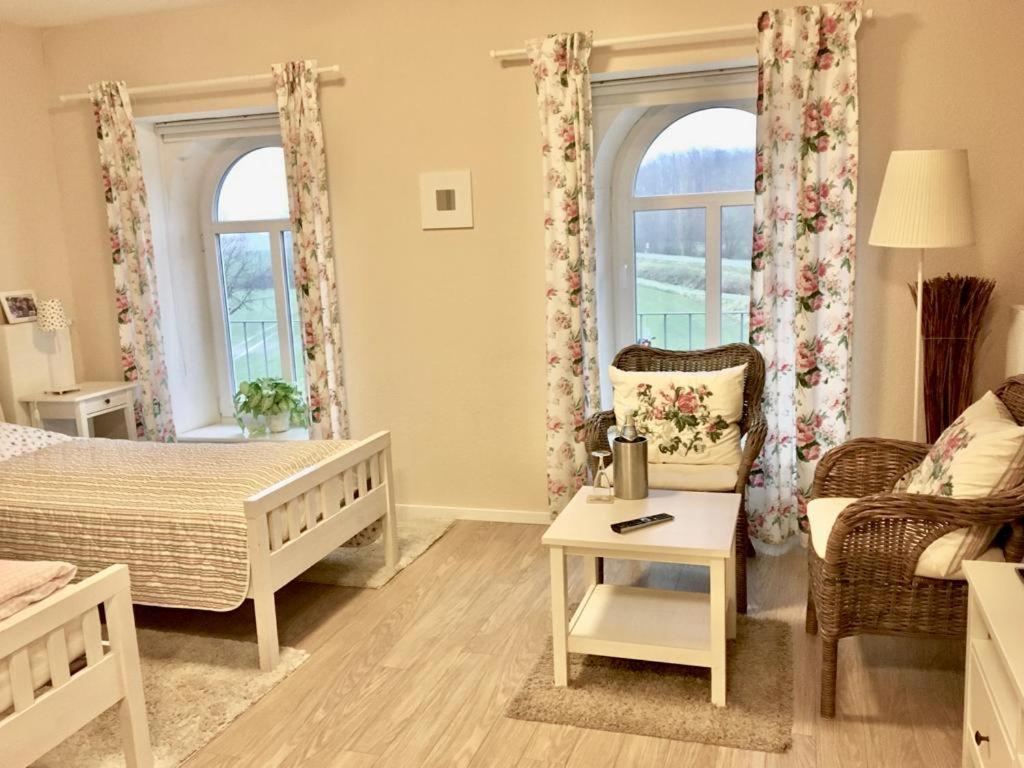 a bedroom with a bed and a chair and two windows at Station L in Langballig