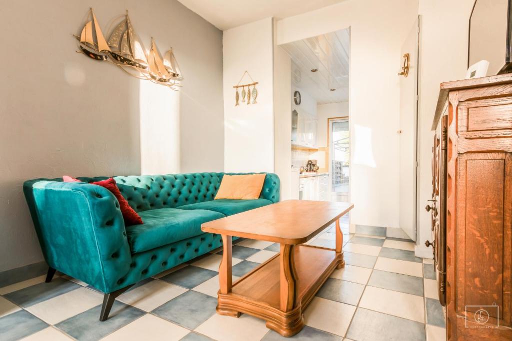 uma sala de estar com um sofá verde e uma mesa em maison jardin terrasse em Le Tréport