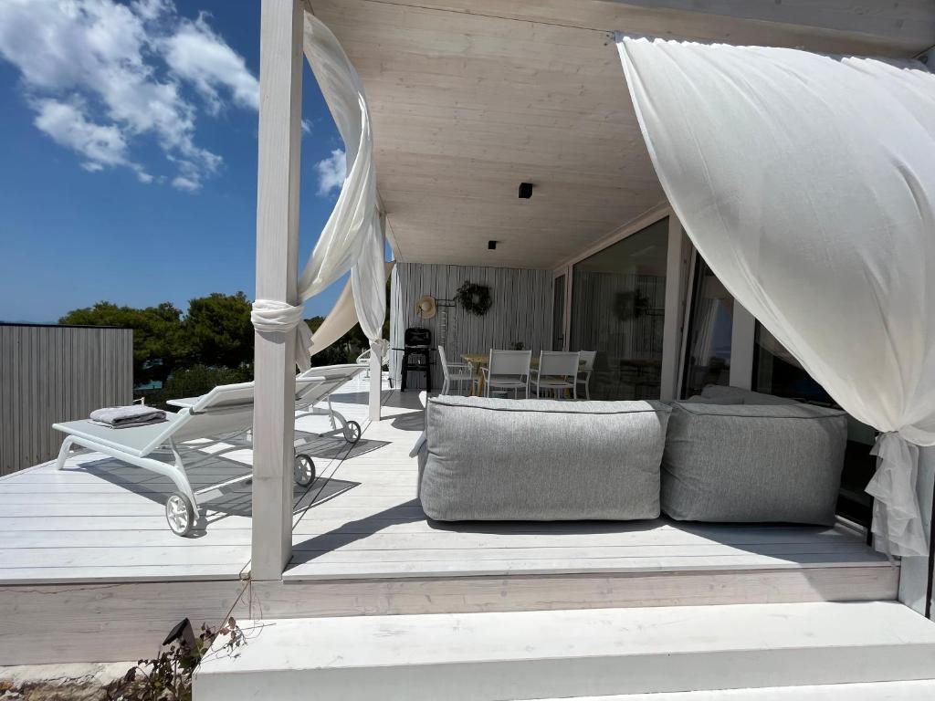 a wooden deck with a couch and chairs on it at BUQEZ ECO RESORT - Beach Villas 2 and 8 - Seaview, new wifi! in Drage