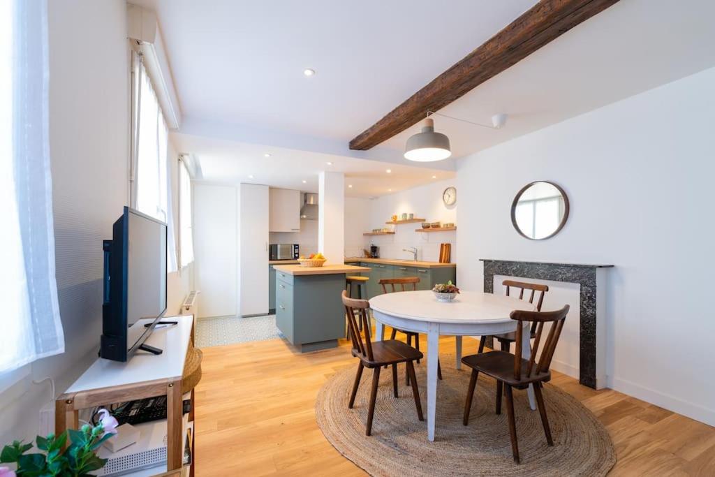 ein Wohnzimmer mit einem Tisch und Stühlen sowie eine Küche in der Unterkunft Appartement Meuse & Mono, en hyper centre in Charleville-Mézières