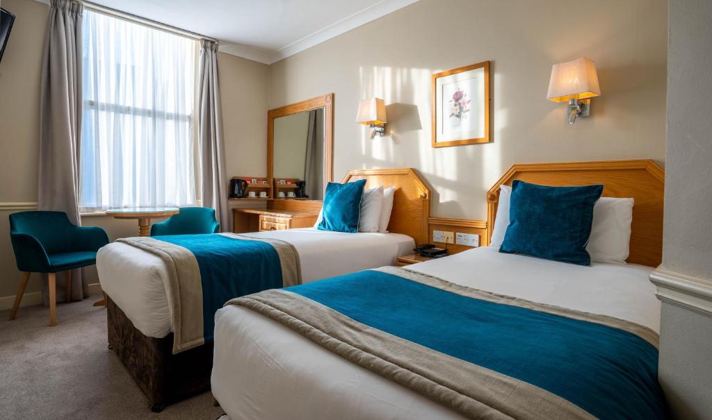 two beds in a hotel room with blue pillows at Harcourt Hotel in Dublin
