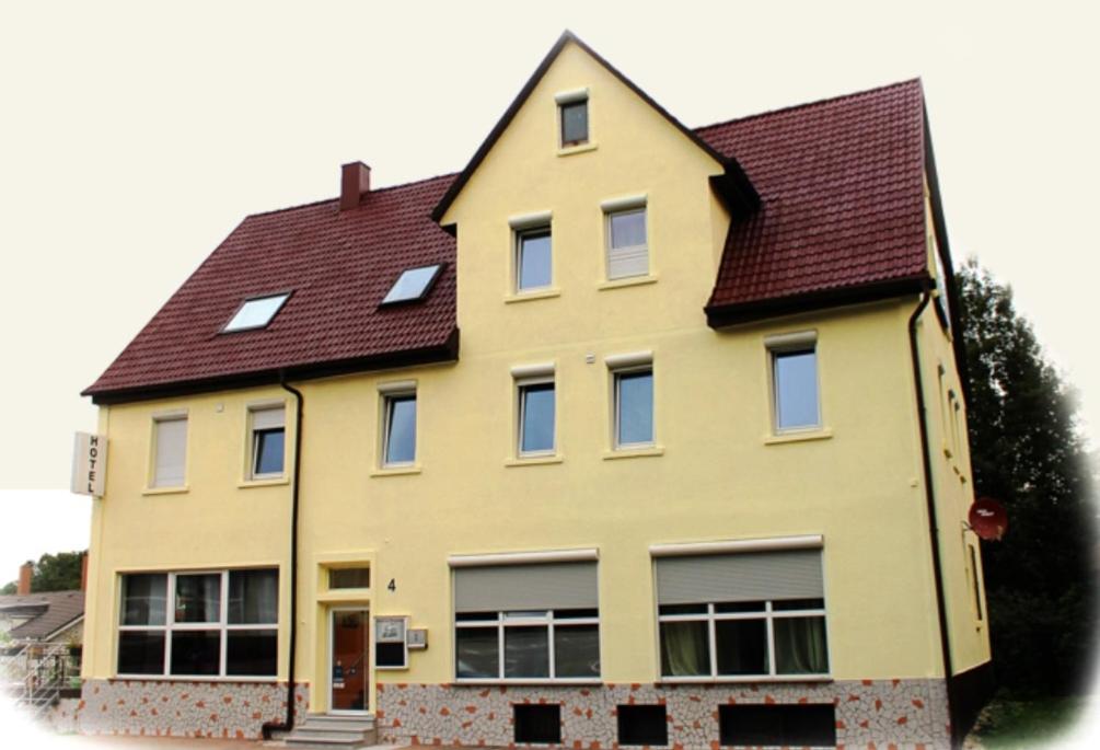 ein großes gelbes Haus mit braunem Dach in der Unterkunft HOTEL Eisenbahn in Crailsheim