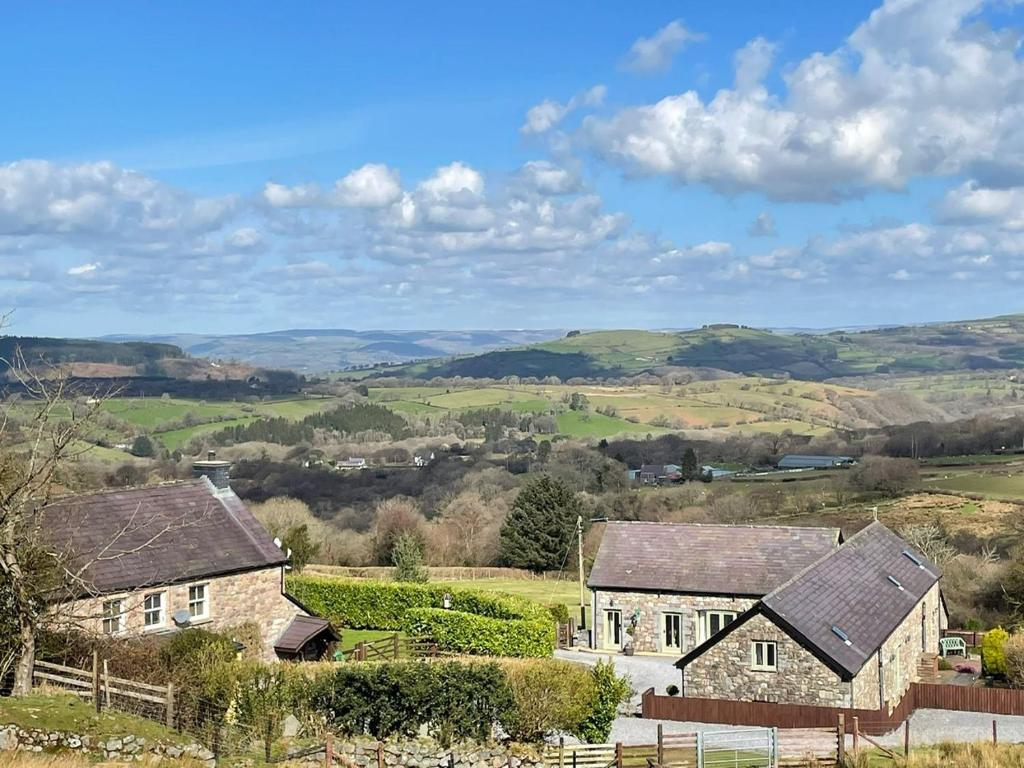 a group of houses in a field with hills in the background at Rhiwddu Barns in Llangadog