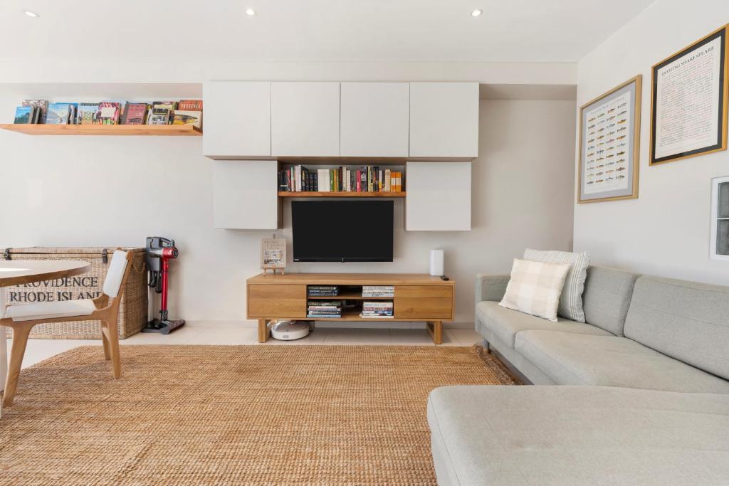 een woonkamer met een bank en een tv bij Beach Bliss 1BR Retreat Prime Bondi Courtyard in Sydney